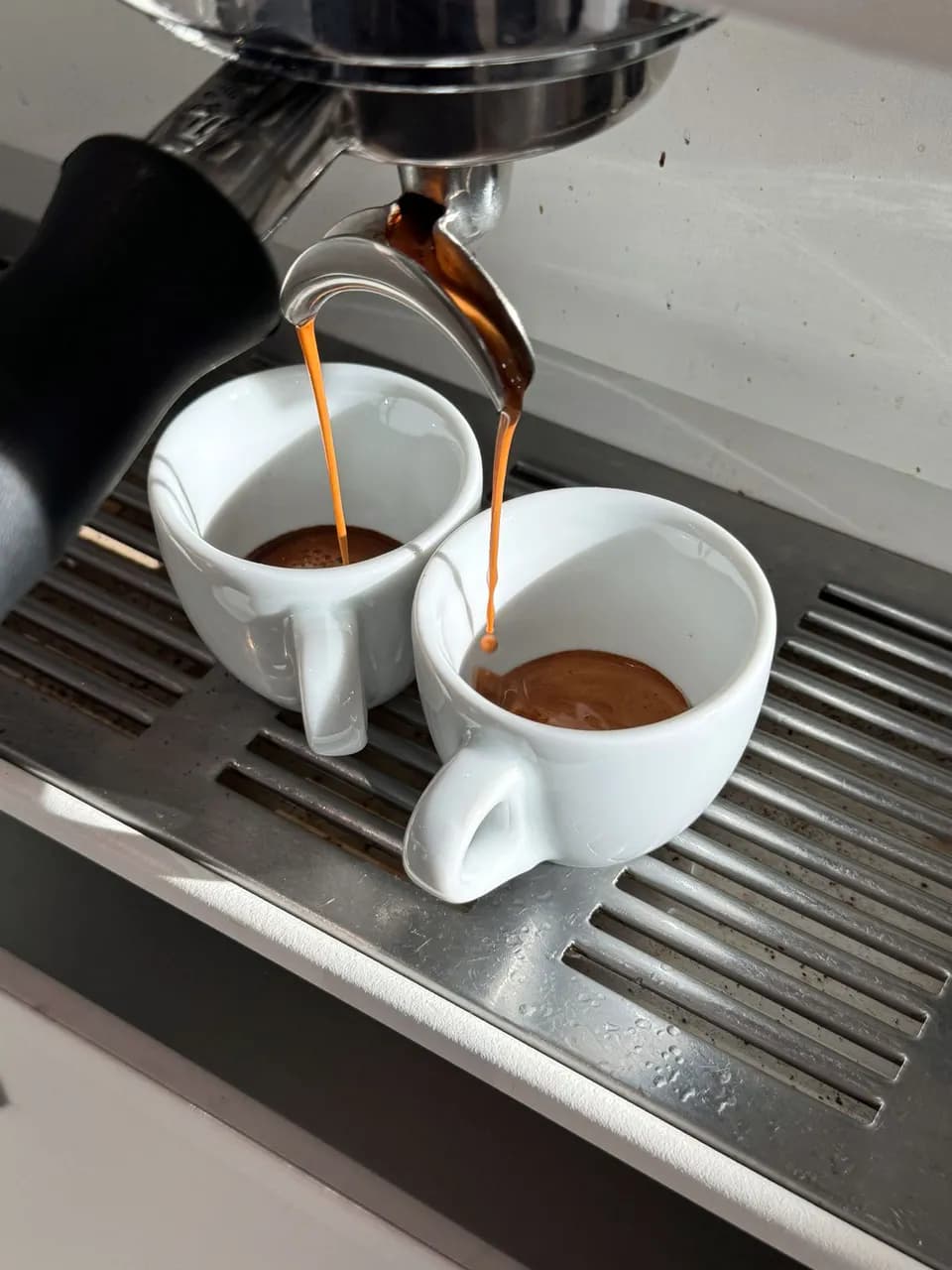 Espresso läuft aus dem doppelten Auslauf in zwei vorgewärmte Tassen